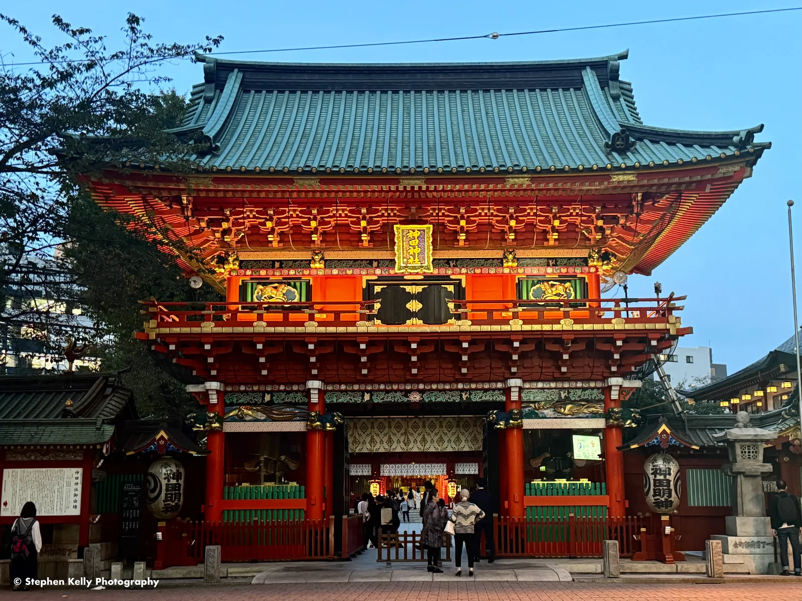 Kanda Myojin’s red Zuishin-mon entrance gate at dusk, photographed by Stephen Kelly in October 2023.